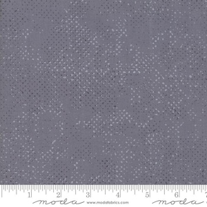 Peut inclure: Gros plan sur un tissu gris avec un motif moucheté. Le tissu a une règle le long du bord inférieur. Le motif se compose de petits points irréguliers dans les tons de gris et de blanc, dispersés sur la surface.