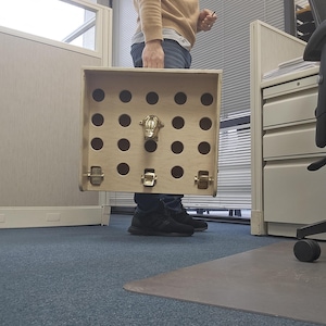May include: A wooden box with a hinged lid and a metal latch. The box has a series of holes in the front, and a metal animal head is attached to the front of the box.