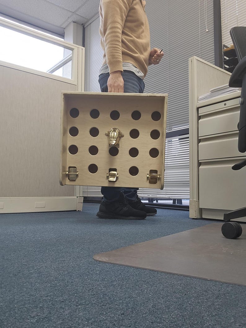 May include: A wooden box with a hinged lid and a metal latch. The box has a series of holes in the front, and a metal animal head is attached to the front of the box.