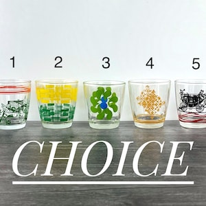 May include: Five clear glass tumblers with different colourful designs. The tumblers are numbered 1 through 5. The designs include a floral pattern, a plaid pattern, a geometric pattern, a floral pattern, and a horse-drawn carriage.