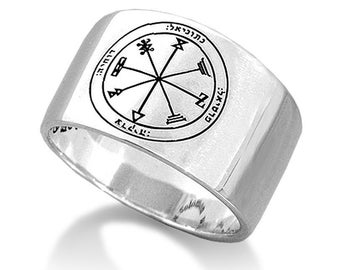 May include: A silver ring with a square face featuring a circular design with Hebrew text and symbols. The ring is a signet ring with a wide band.
