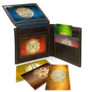 Può includere: Un portafoglio in pelle marrone con più tasche e fessure. Il portafoglio presenta una varietà di carte colorate con disegni intricati e testo in ebraico.