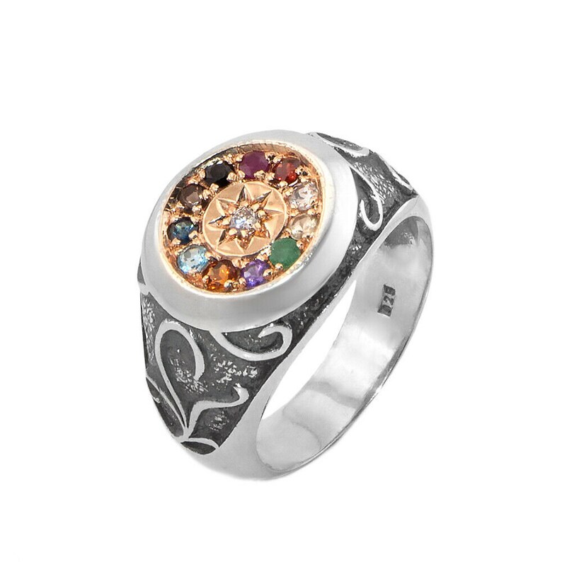 May include: A silver ring with a round, multi-colored gemstone setting. The ring has a detailed, ornate design and a gold-toned center with a star-shaped design.