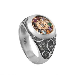 May include: A silver ring with a round, multi-colored gemstone setting. The ring features a detailed, ornate design and a star-shaped center stone.