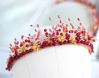 May include: A red and gold beaded crown with a floral design. The crown is made of small red beads and gold wire, and it has a delicate floral pattern.