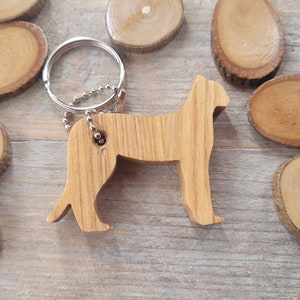 Può includere: Portachiavi in legno con la silhouette di un gatto. Il portachiavi è in legno marrone chiaro e ha un anello portachiavi argentato.