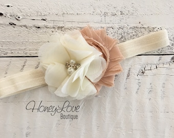 May include: A white and peach flower headband with pearl accents. The headband is made of a soft, stretchy material and is perfect for adding a touch of elegance to any outfit.