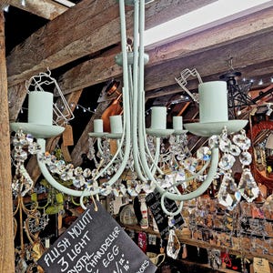 Op de afbeelding: Een eendenei blauwe plafondlamp met kristallen accenten. De kroonluchter heeft drie lampen en is 30 cm breed en 40 cm hoog. De tekst op het bord luidt "FLUSH MOUNT 3 LIGHT CRYSTAL CHANDELIER DUCK EGG".