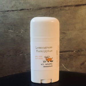 May include: White deodorant stick with a label that says "Lemongrass Eucalyptus all natural deodorant" and features a cartoon goat. The label also says "small batch, hand crafted".