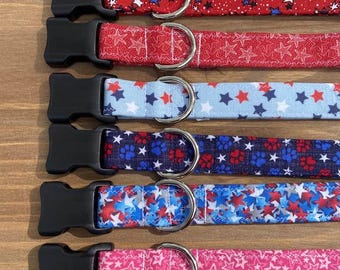 May include: Six different dog collars with a red, white, and blue star pattern. The collars have black buckles and silver D-rings.