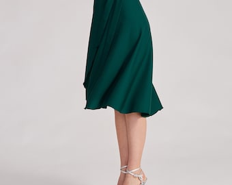 May include: A dark emerald green midi-length wrap skirt featuring a high-waisted design with a side tie closure. The skirt has a smooth, solid-colored fabric that drapes into a flared hemline, falling below the knees with a clean, simple silhouette.