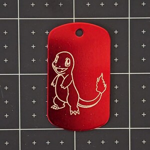 May include: A red metal dog tag with a white engraved image of a cartoon fire-type Pokemon. The Pokemon is standing on all fours with its tail in the air.