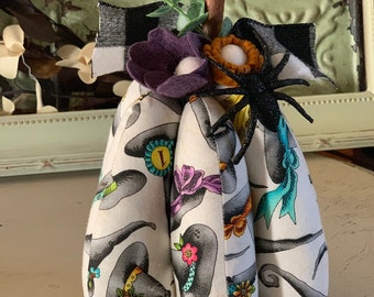 Suffed pumpkin, witches hat fabric, felt flowers, glitter spider, greenery and black buffalo check ribbon, mountain stem
