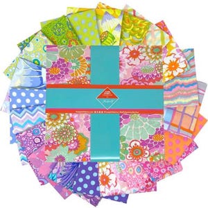 May include: A collection of colorful fabric squares arranged in a circular pattern. The fabrics feature floral, polka dot, and geometric designs in shades of pink, green, blue, and orange. A turquoise band with text wraps around the center of the fabric squares.