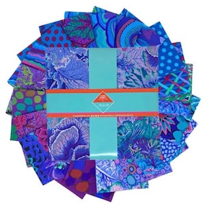 May include: A collection of fabric squares in shades of blue, purple, and green, featuring various patterns like polka dots, floral designs, and abstract swirls. The squares are arranged in a circular pattern and held together with a teal band. The fabric is likely for quilting or crafting.