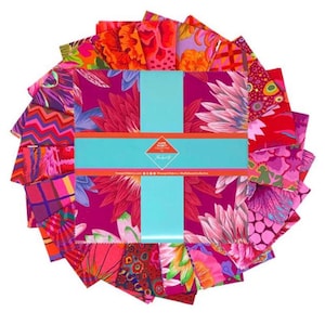 May include: A collection of colorful fabric squares arranged in a circular pattern. The fabrics feature floral and abstract designs in shades of pink, red, orange, and purple. A turquoise band wraps around the center, with text and a logo.