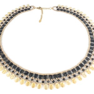 Peut inclure: Un collier de perles dorées et noires avec un motif géométrique et des perles dorées en forme de larme.