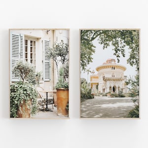 May include: Two framed prints of a European-style building. The left print shows a building with a cafe patio with a table and chairs. The right print shows a building with a dome roof and a garden.