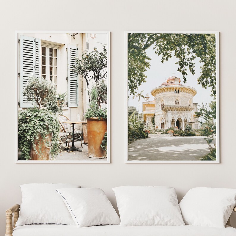 May include: Two framed prints of architectural scenes. The first print shows a patio with a table and chairs, surrounded by lush greenery. The second print shows a white building with a domed roof, surrounded by trees and a paved path.