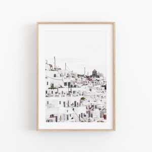 May include: A photograph of a white village built on a hillside. The buildings are all white with blue accents and there are many windows and balconies. The village is located in a sunny, warm climate.