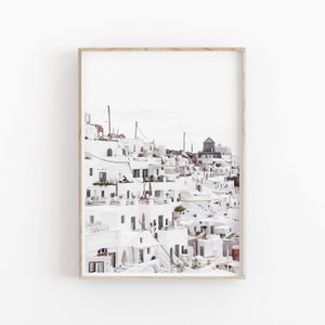 May include: A photograph of a white, hillside village with a cluster of buildings, some with blue doors and windows. The buildings are stacked on top of each other, creating a unique and picturesque scene.