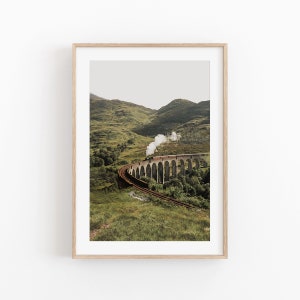 May include: A train travels across a stone viaduct in a mountainous landscape. The train is emitting steam as it moves along the tracks. The landscape is green and lush, with rolling hills and trees.