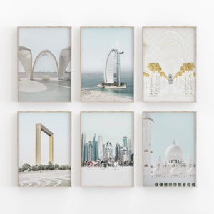 May include: A set of six framed prints showcasing iconic landmarks of Dubai, including the Burj Al Arab, the Frame, and the Sheikh Zayed Grand Mosque. The prints are presented in a minimalist style with a white background and a light blue hue.