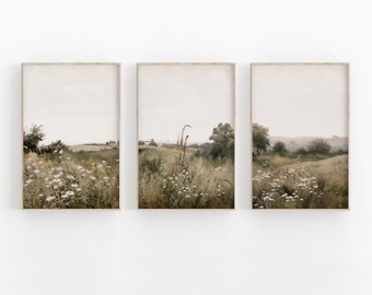 May include: A set of three framed prints featuring a watercolor painting of a field of wildflowers with a distant view of a small town. The prints are in a muted color palette of greens, browns, and whites.