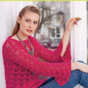May include: A pink crocheted top with a lacy pattern and long sleeves. The top has a slightly flared hem and a relaxed fit.