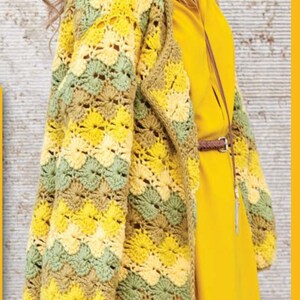 K&ouml;nnte beinhalten: Ein langer H&auml;kelcardigan mit einem gelben, gr&uuml;nen und braunen Farbmuster. Der Cardigan hat eine lockere Passform und einen Schalkragen.