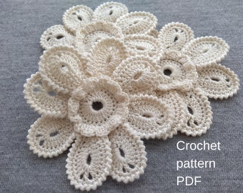 May include: A crocheted flower pattern in white yarn. The pattern is made up of several layers of petals, with a smaller flower in the center. The text "Crochet pattern PDF" is written below the flower.