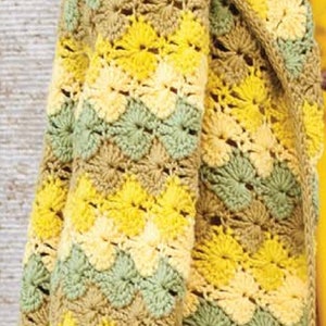 K&ouml;nnte beinhalten: Eine geh&auml;kelte Strickjacke in einem gelben, gr&uuml;nen und braunen Farbmuster. Die Strickjacke hat eine lockere Passform und einen langen, offenen Vorderteil.