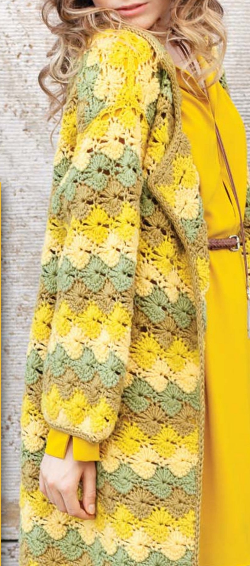K&ouml;nnte beinhalten: Eine geh&auml;kelte Strickjacke mit einem gelben, gr&uuml;nen und braunen Farbmuster. Die Strickjacke hat einen langen, offenen Vorderteil und lange &Auml;rmel.