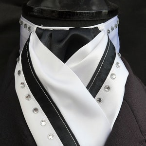 Puede incluir: Fular de cuello de satén blanco y negro con ribete de satén negro y detalles de pedrería.