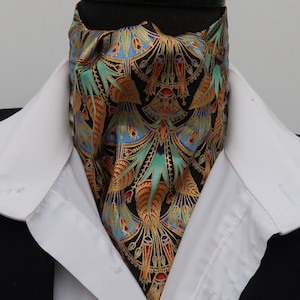 Peut inclure: Un ascot à motifs noirs, turquoise, or et bleu, porté avec une chemise à col blanc et une veste de costume noire. L'ascot présente un motif complexe avec des éléments floraux et géométriques.