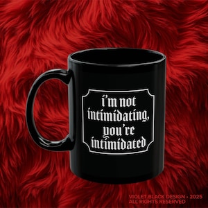 May include: Black coffee mug with a white graphic that says "I'm not intimidating, you're intimidated".