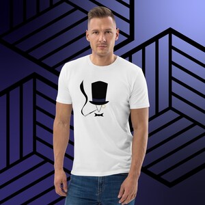 Peut inclure: Un t-shirt blanc avec une illustration en noir et blanc d'une personne portant un haut-de-forme, un monocle et un nœud papillon. La personne fume une pipe.