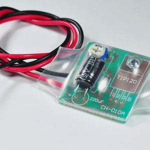 May include: A green circuit board with a black capacitor, a TIP120 transistor, and a 220uF capacitor. The board is labeled CH-010A. The board is encased in clear plastic.