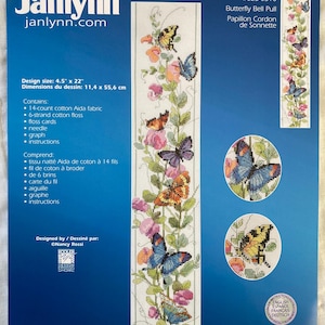 May include: A counted cross-stitch kit by Janlynn, featuring a butterfly bell pull design. The design size is 4.5" x 22". The kit includes 14-count cotton Aida fabric, floss, needle, and instructions. The kit features colorful butterflies and flowers.