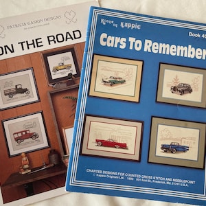 May include: Two vintage cross-stitch pattern books. One titled "ON THE ROAD" features framed truck designs. The other, "Cars To Remember," showcases framed car designs on a blue cover. Both books are for counted cross stitch.
