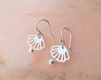 May include: A pair of silver-toned drop earrings featuring a cutout fan-shaped shell charm. Each earring hangs from a curved hook wire and includes a small, smooth spherical bead attached to the bottom edge of the shell-shaped metal component.