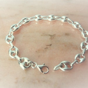 May include: A silver chain bracelet with a mariner link design. The bracelet has a lobster clasp closure.