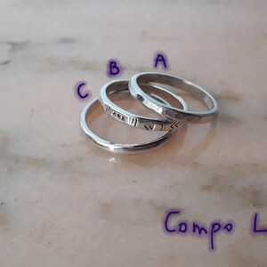 May include: Three silver rings are shown, each with a distinct design. Ring A has a hammered texture, Ring B features geometric etchings, and Ring C has a smooth, polished surface. The rings are arranged on a light-coloured surface. The text "Compo L" is written in purple.