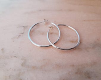 May include: A pair of silver hoop earrings. The hoops are smooth and have a polished finish.
