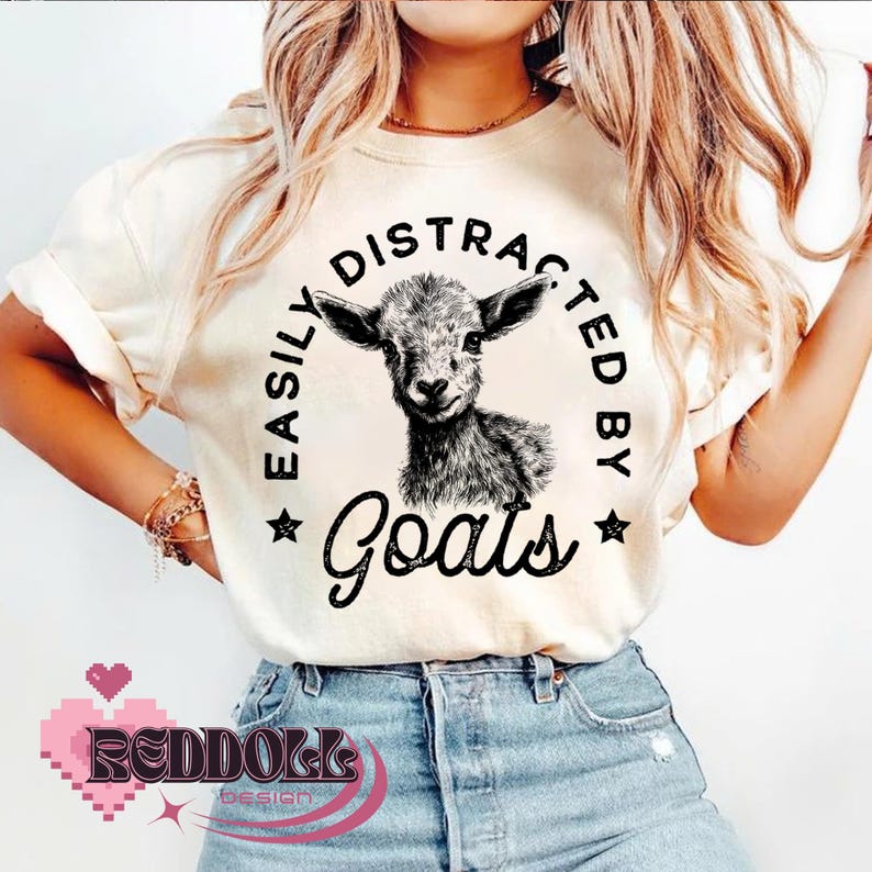 May include: A white t-shirt with a black and white illustration of a goat and the text "Easily Distracted By Goats".