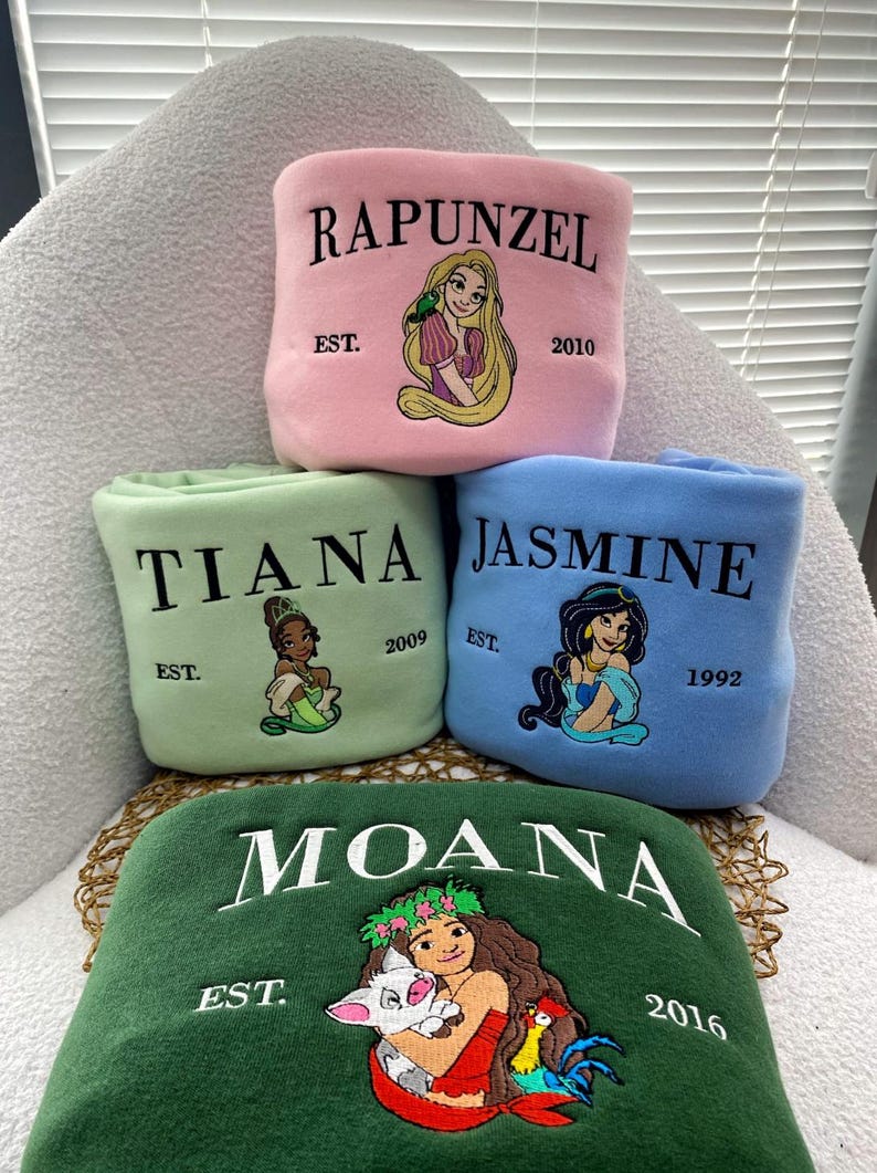 Może przedstawiać: Cztery haftowane polarowe koce z księżniczkami Disneya: Roszpunką, Tianą, Jaśminą i Moaną. Każdy koc jest w innym kolorze: r&oacute;żowym, zielonym, niebieskim i ciemnozielonym. Każdy koc ma imię księżniczki, obraz i rok założenia.