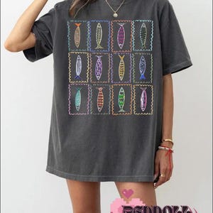 May include: A charcoal gray oversized t-shirt with a graphic print of a grid of colorful fish in frames.