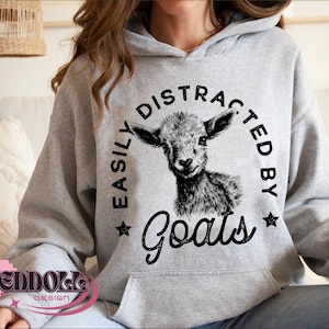 May include: A gray hoodie with a black graphic that says "Easily Distracted By Goats" and features a black and white illustration of a goat's head.