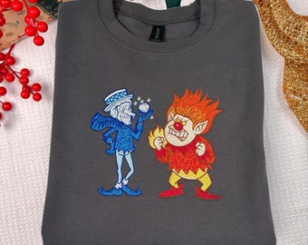 May include: Dark gray sweatshirt featuring embroidered cartoon characters: a blue Frosty-like figure and a fiery red imp. The Frosty figure holds a snowball, while the imp has flames. A cozy, festive garment.