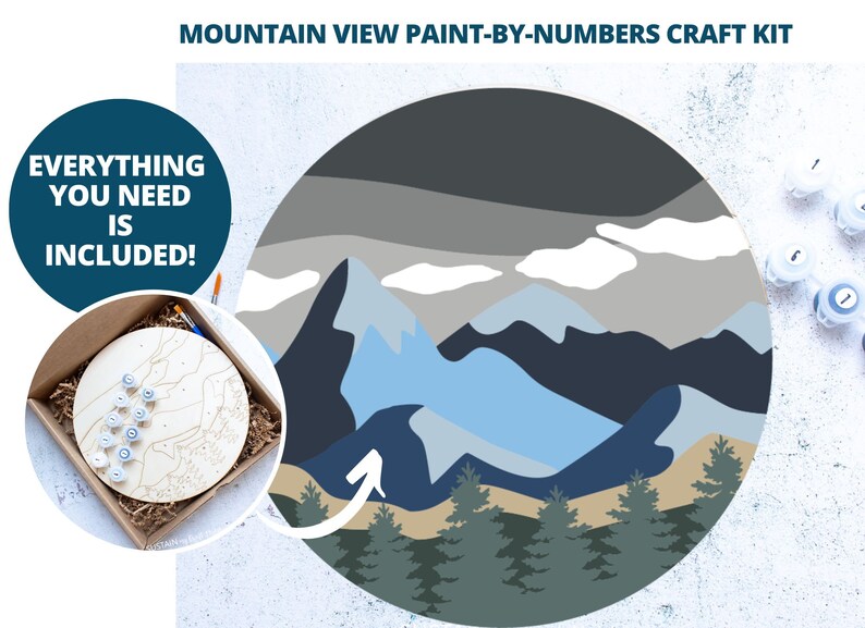 Peut inclure: Un kit de peinture par num&eacute;ros repr&eacute;sentant un paysage de montagne avec une palette de couleurs bleue, grise et blanche. Le kit comprend une toile en bois, des pots de peinture et des pinceaux. Le texte "Tout ce dont vous avez besoin est inclus !" est affich&eacute; dans un cercle bleu.